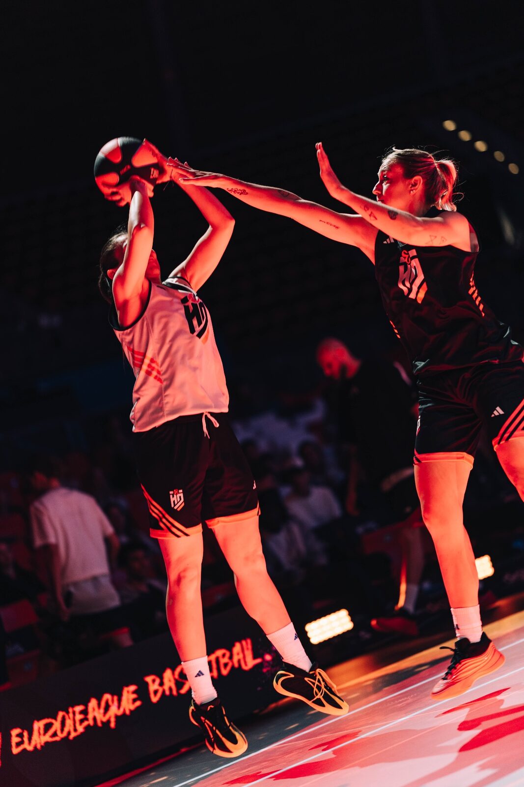 Azione di gioco fisico in area: due giocatrici di basket Euroleague Women contendono il pallone sotto le luci del parquet